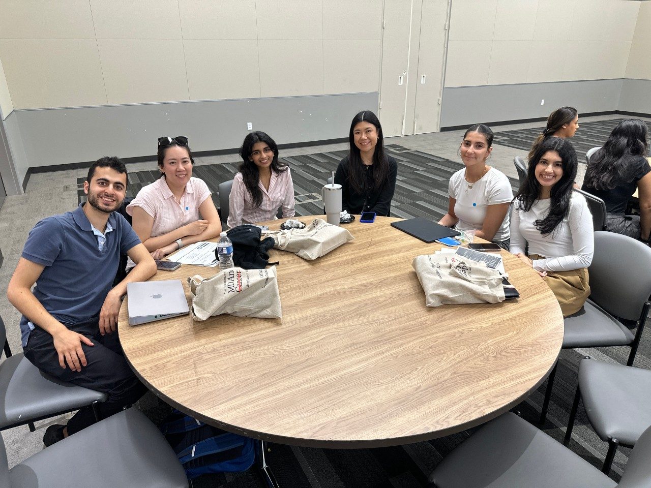 a group of CATALYST Summer Training Program students sitting at a round table posing for a photo
