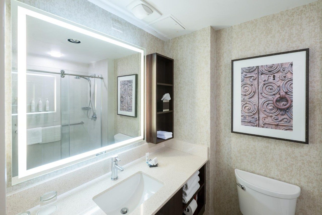 Bathroom sink and mirror in a room with two queen beds and kitchenette