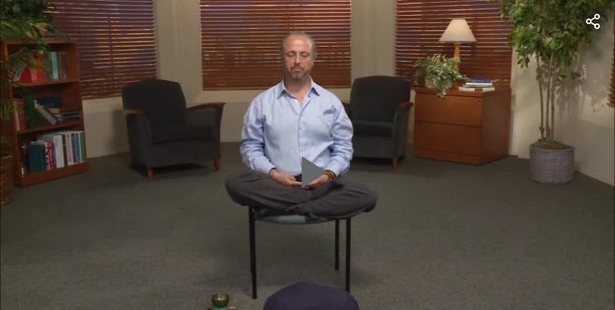 Photo of man sitting cross-legged on a chair