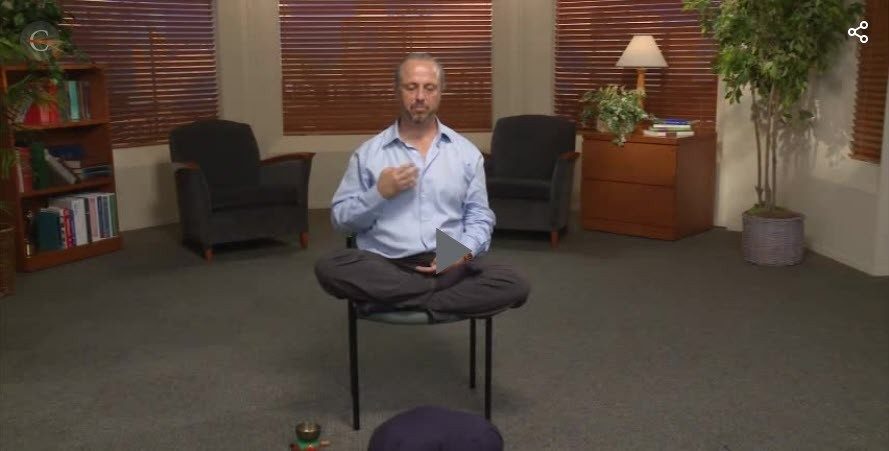 Photo of man sitting cross-legged on a chair