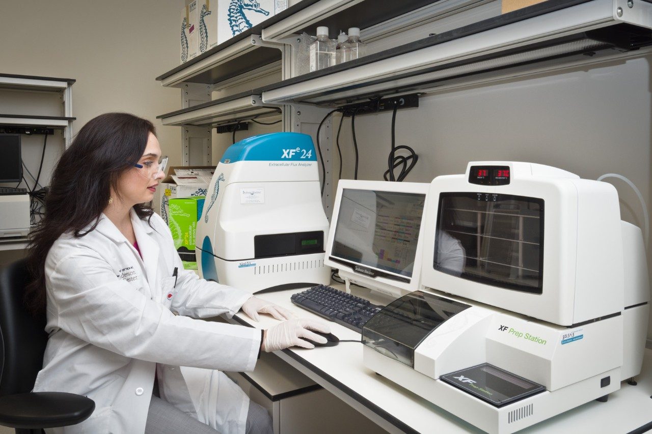 A woman in a white coat works in a lab