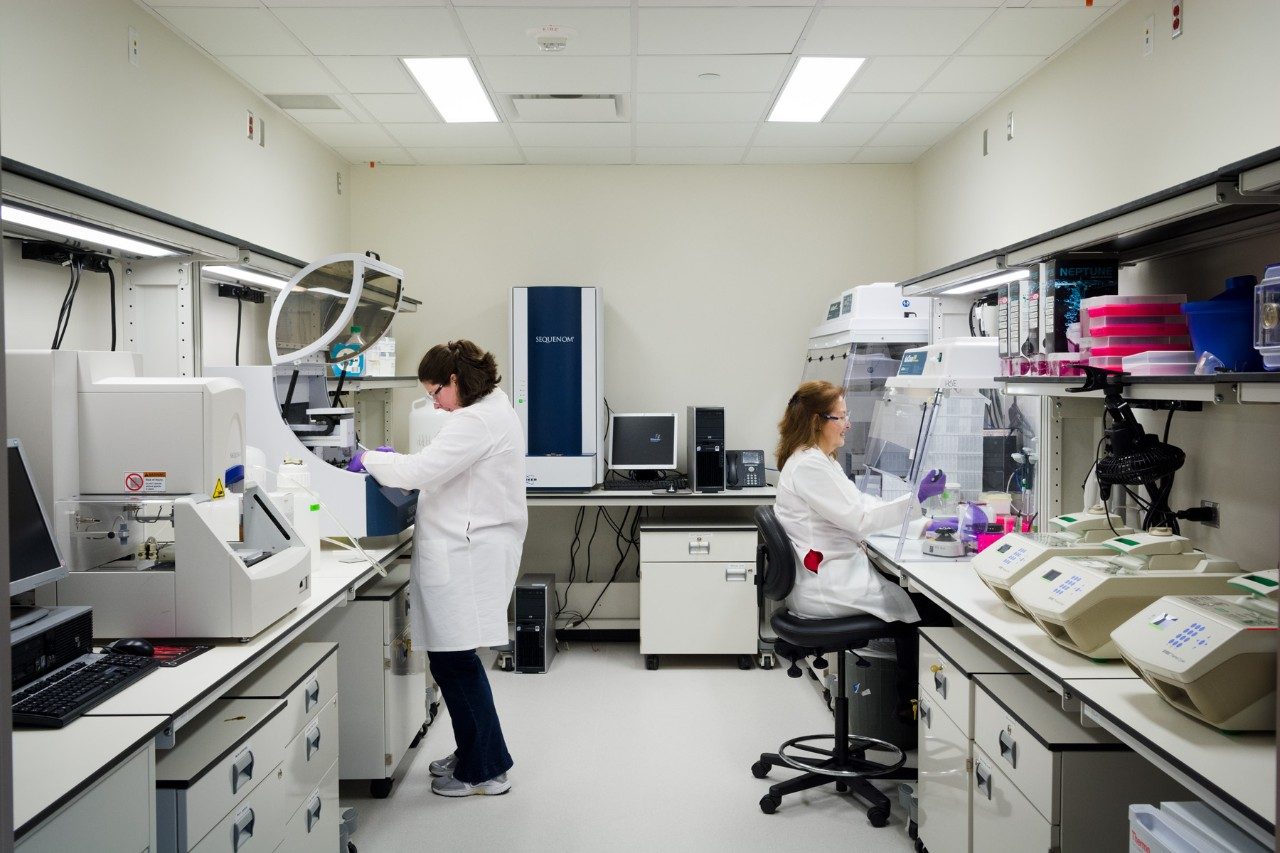 Two people in white coats work in a lab