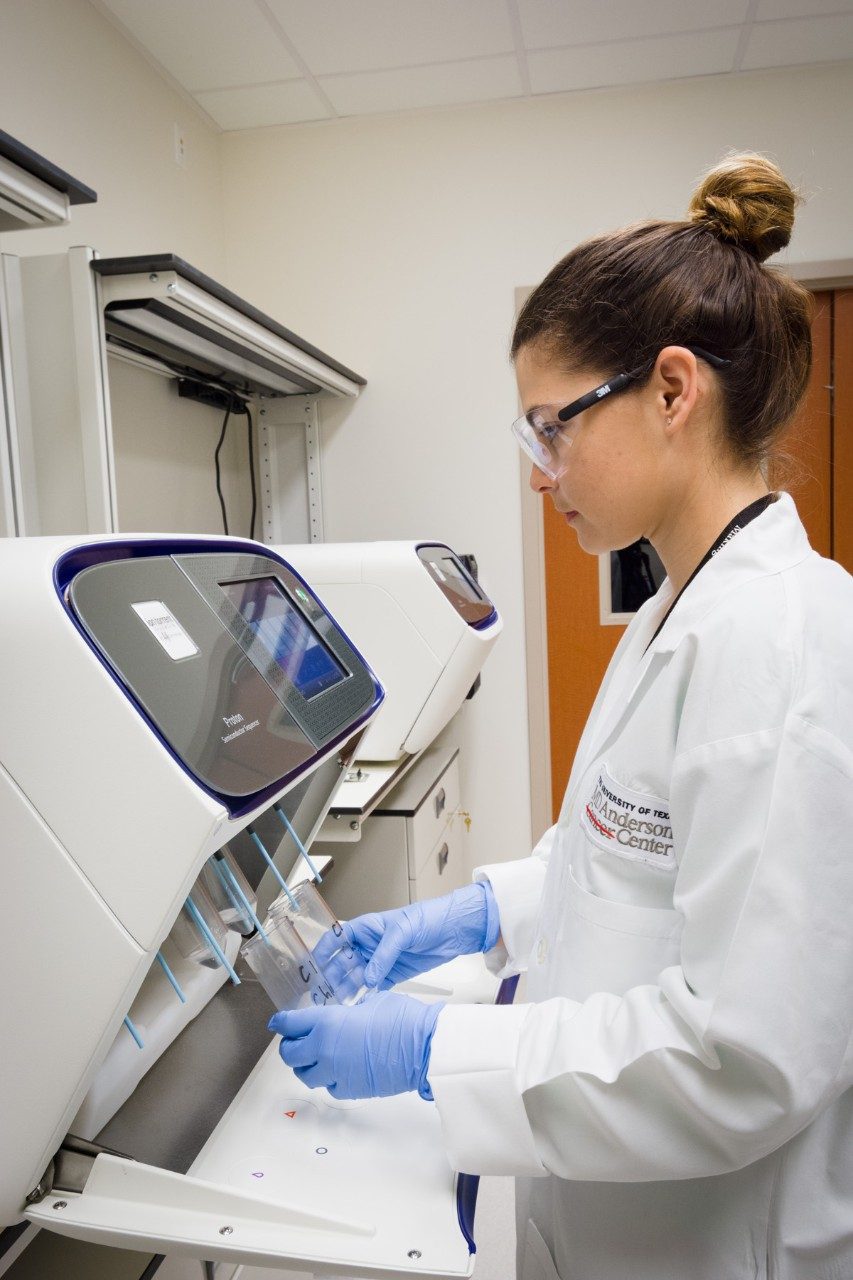 A woman in a white coat works in a lab
