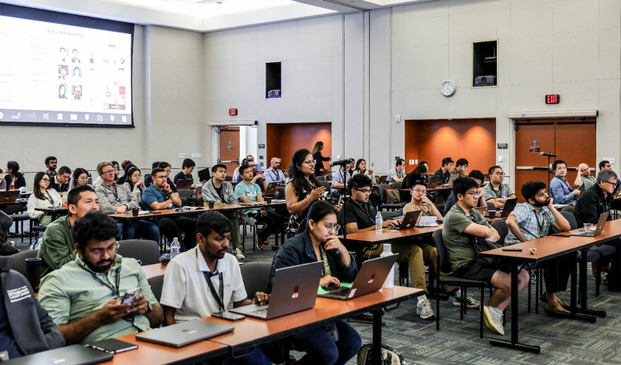 A room full of people sitting at tables with laptops