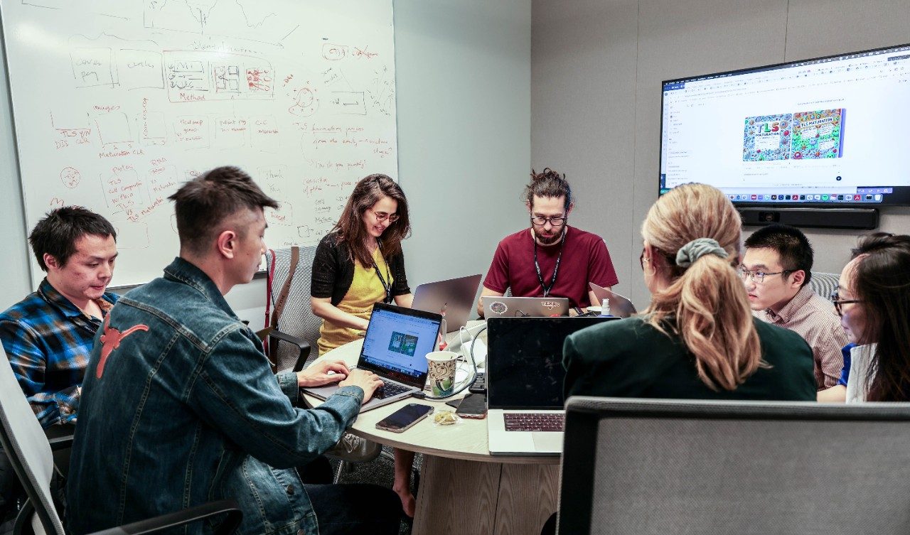 A group of people sit around a table an appear to be working