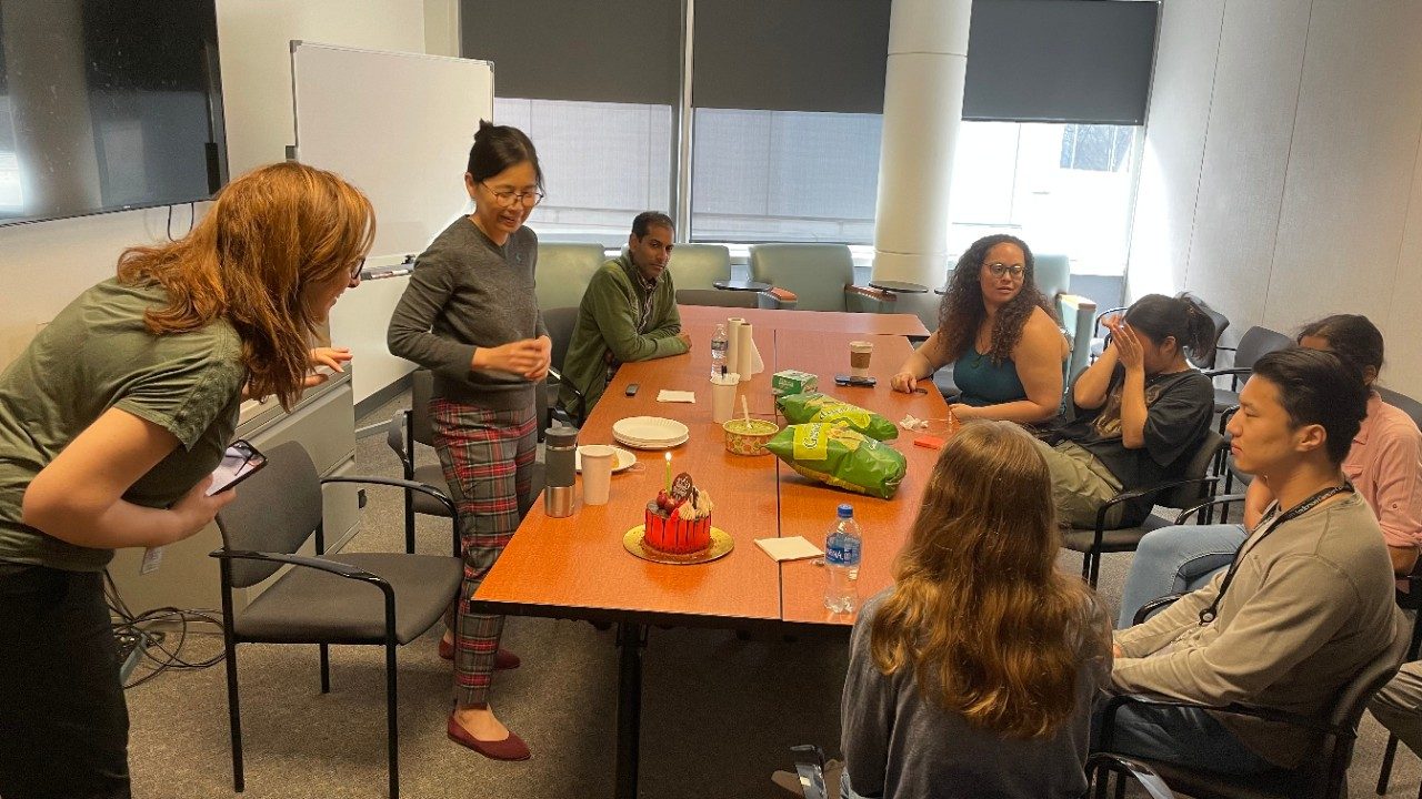 Group of people sitting and standing around a conference room table