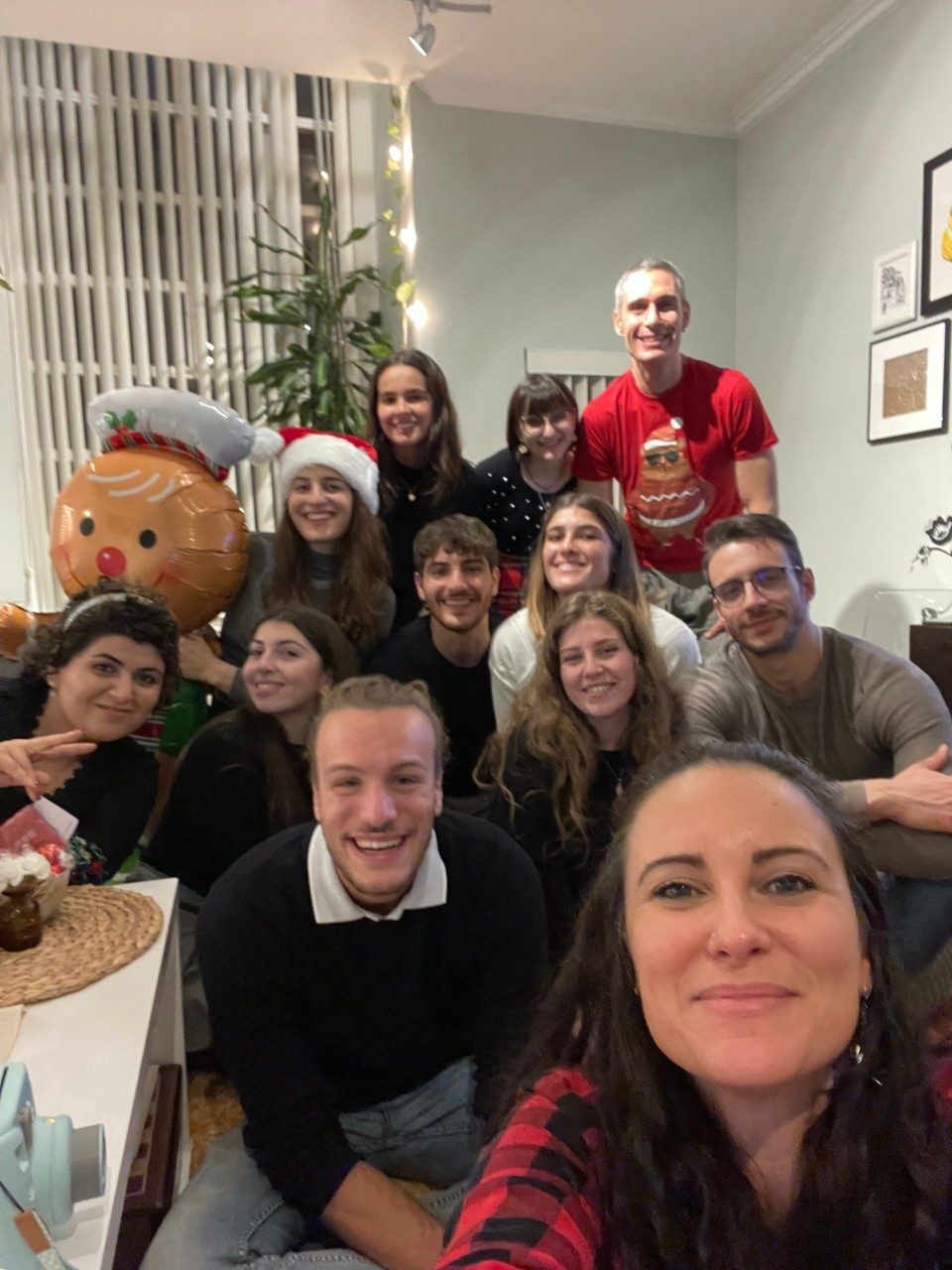 Selfie of group of people in front of a Christmas tree and gingerbread man balloon