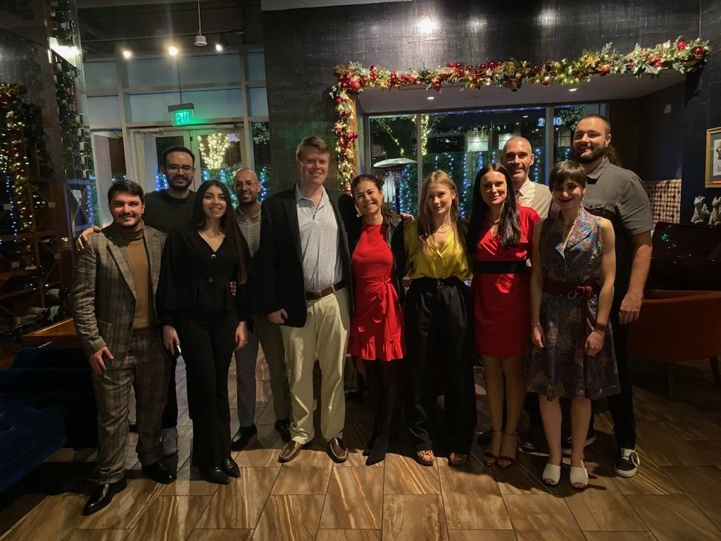 11 people in formal wear, lined up at a holiday event