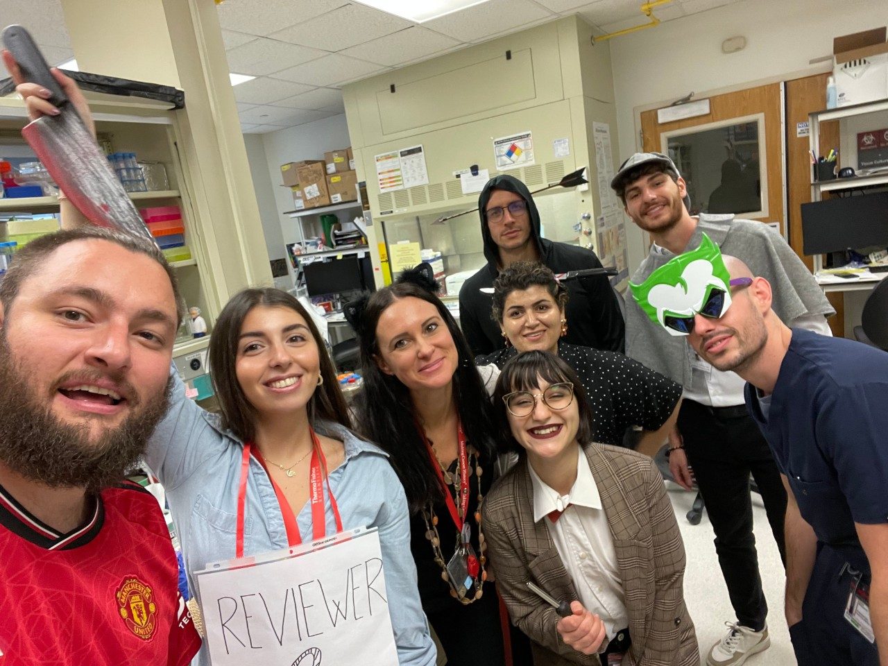 Selfie of 8 people in a lab in Halloween costumes