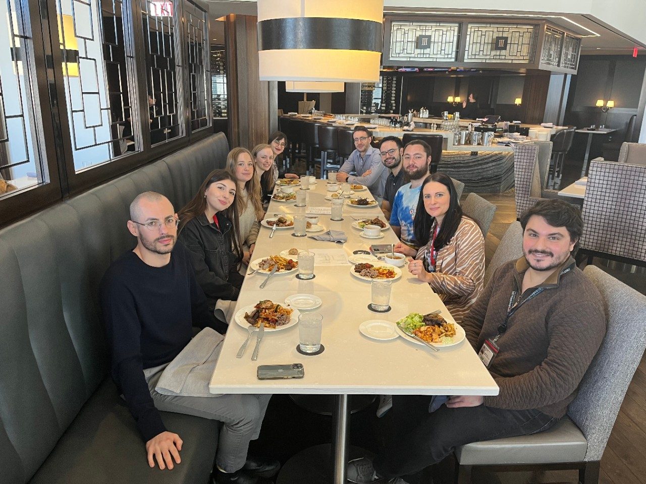 Lab group seated around a long, white rectangular table at a restaurant
