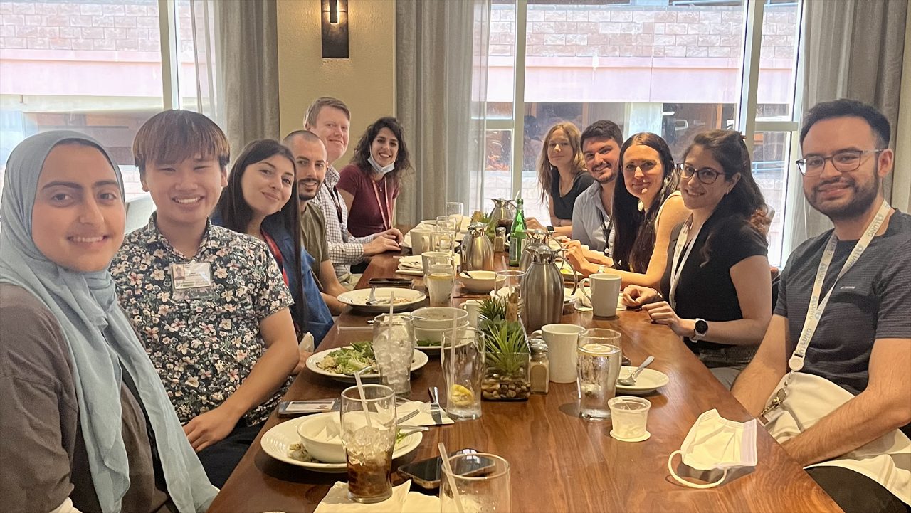 Lab members posed around a wooden table at a restaurant