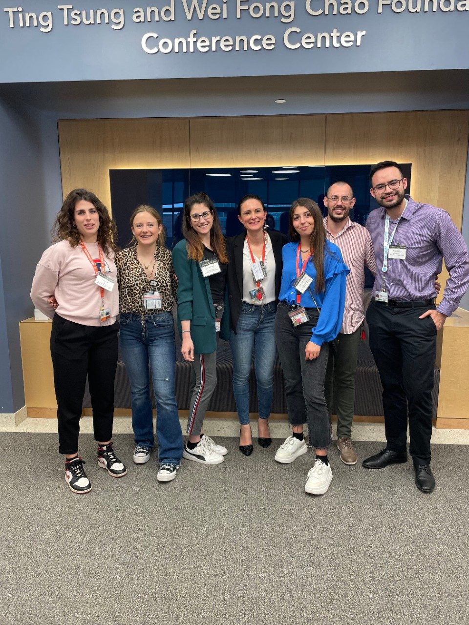 7 trainees lined up and posing under a Conference Center sign outside of an auditorium