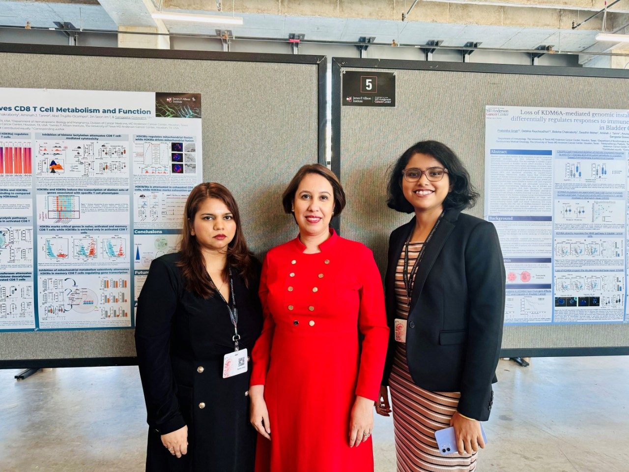 Three women pose in front of poster boards at a conference
