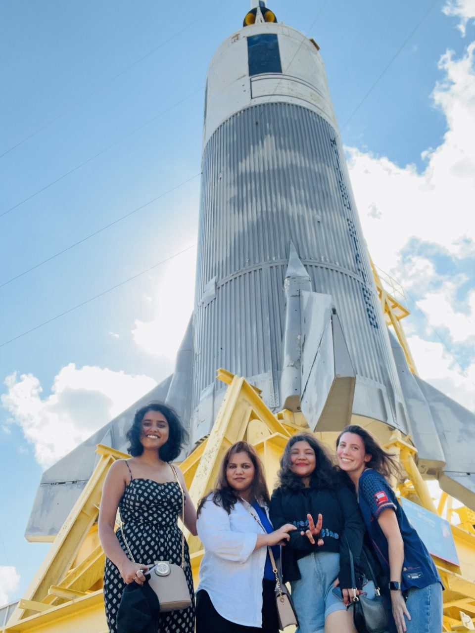 Four lab members pose in front of a rocket