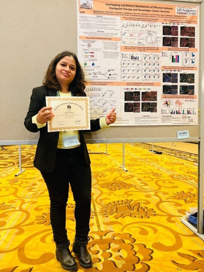 Person posing in front of a poster, holding a certificate and giving a thumbs up