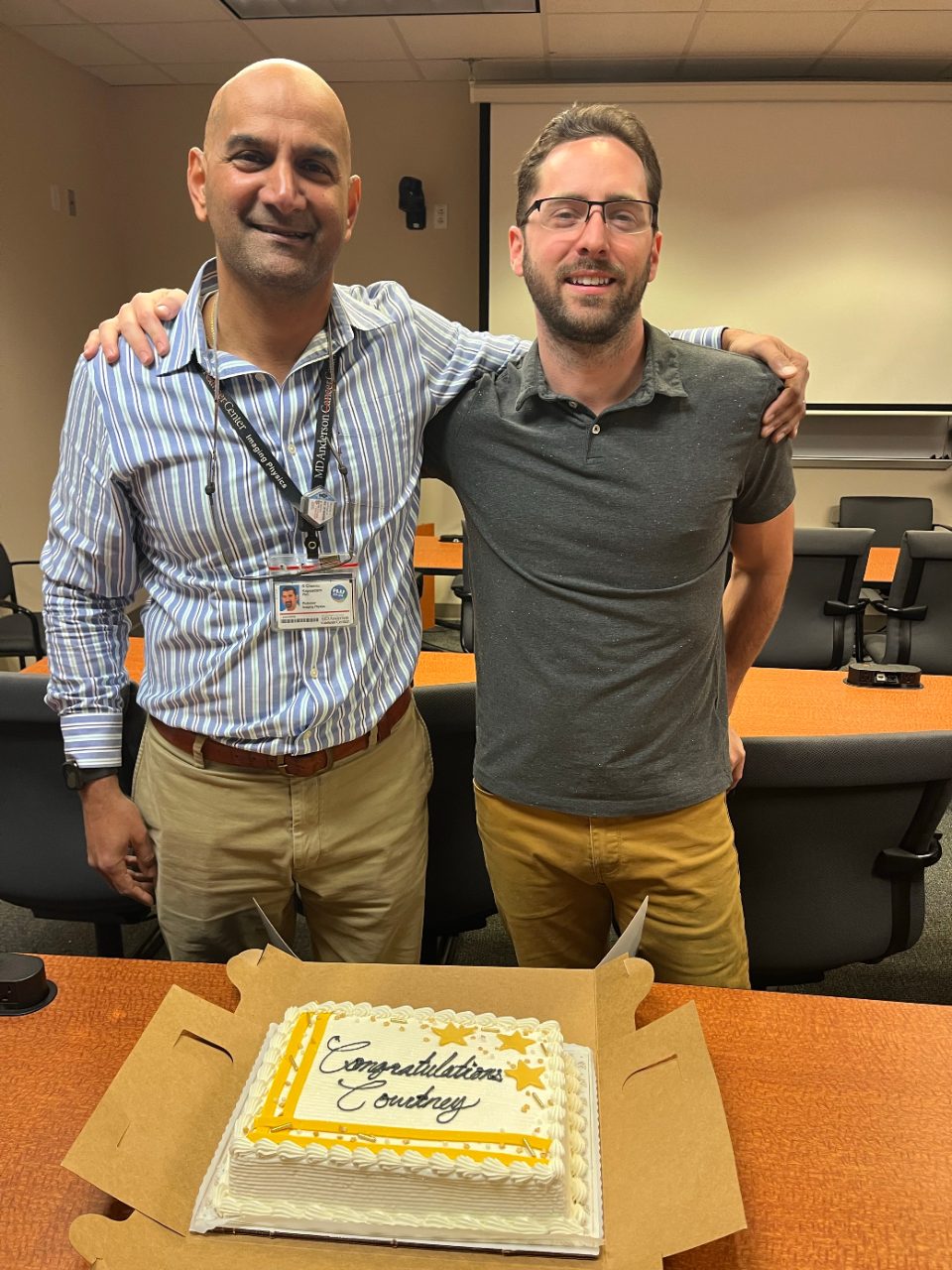 Two men posing with a cake