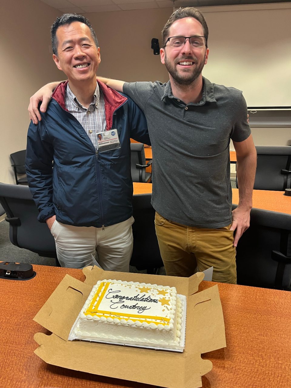 Two men posing with a cake