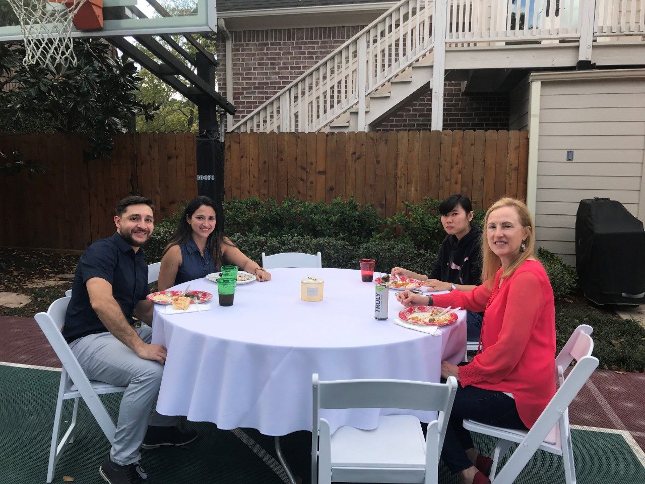 Four people sit at tables outdoors