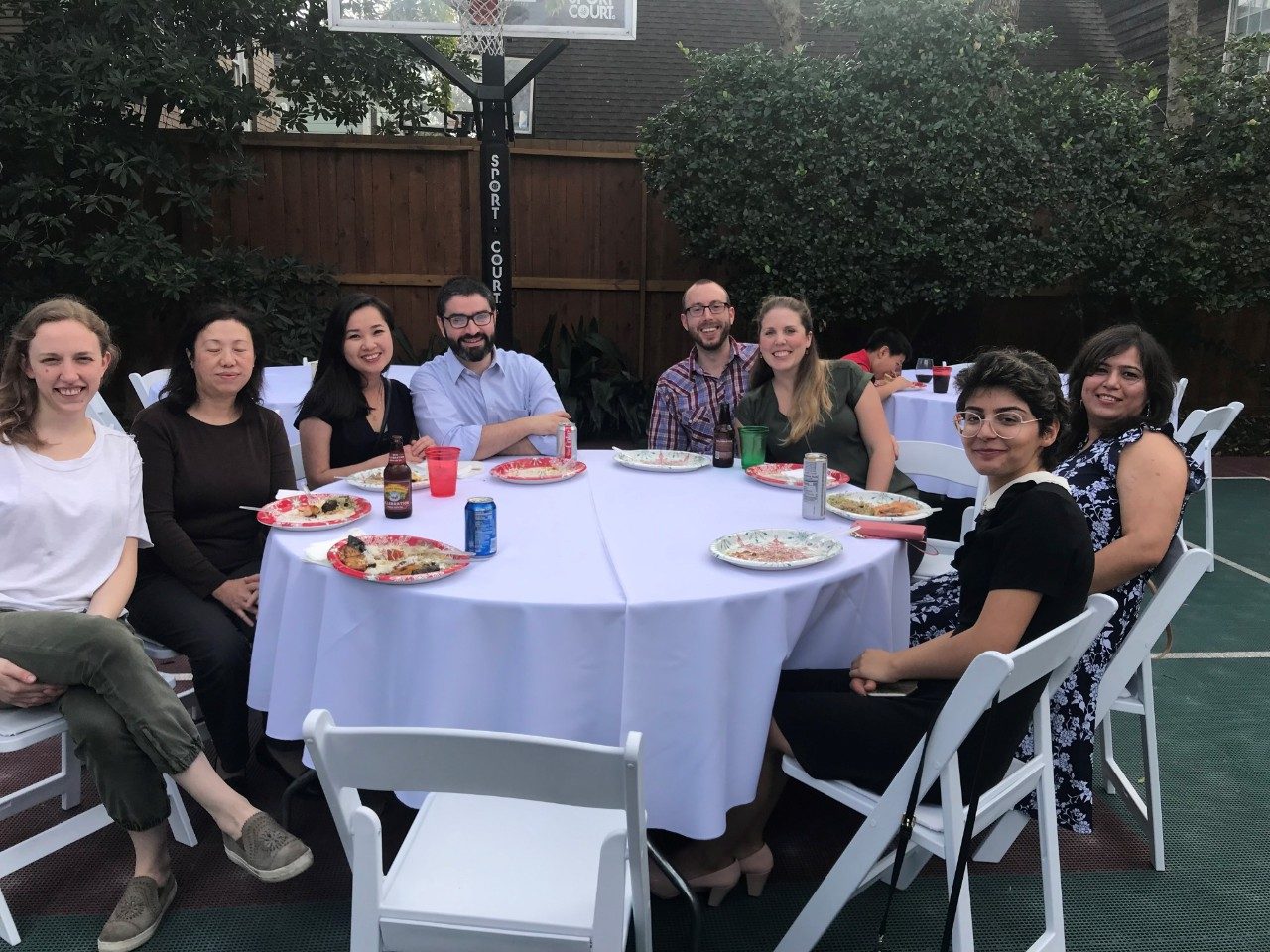 Eight people sit at a table outdoors