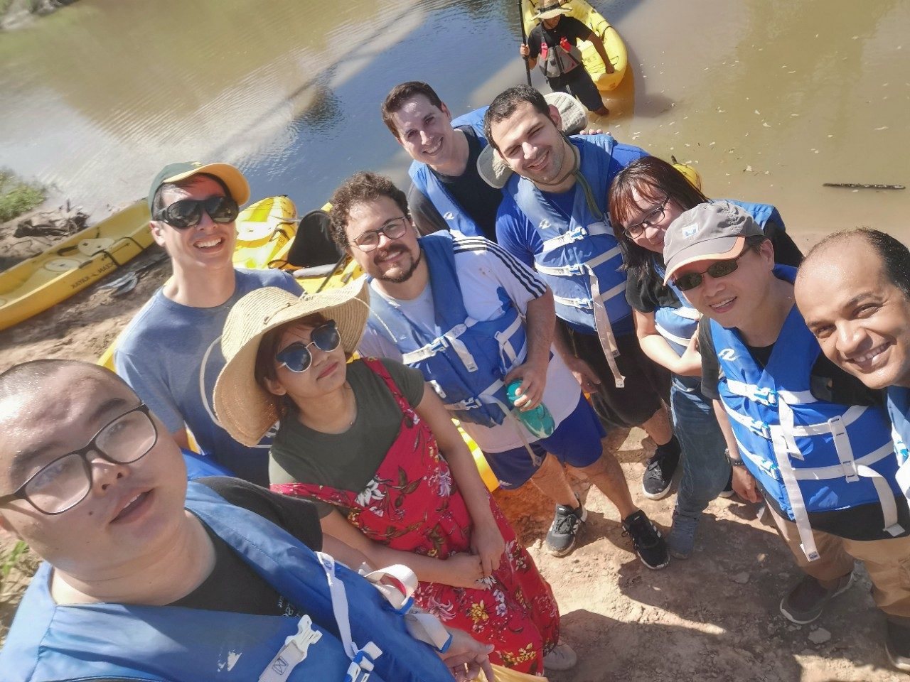 Group selfie with everyone in life vests in front of a river
