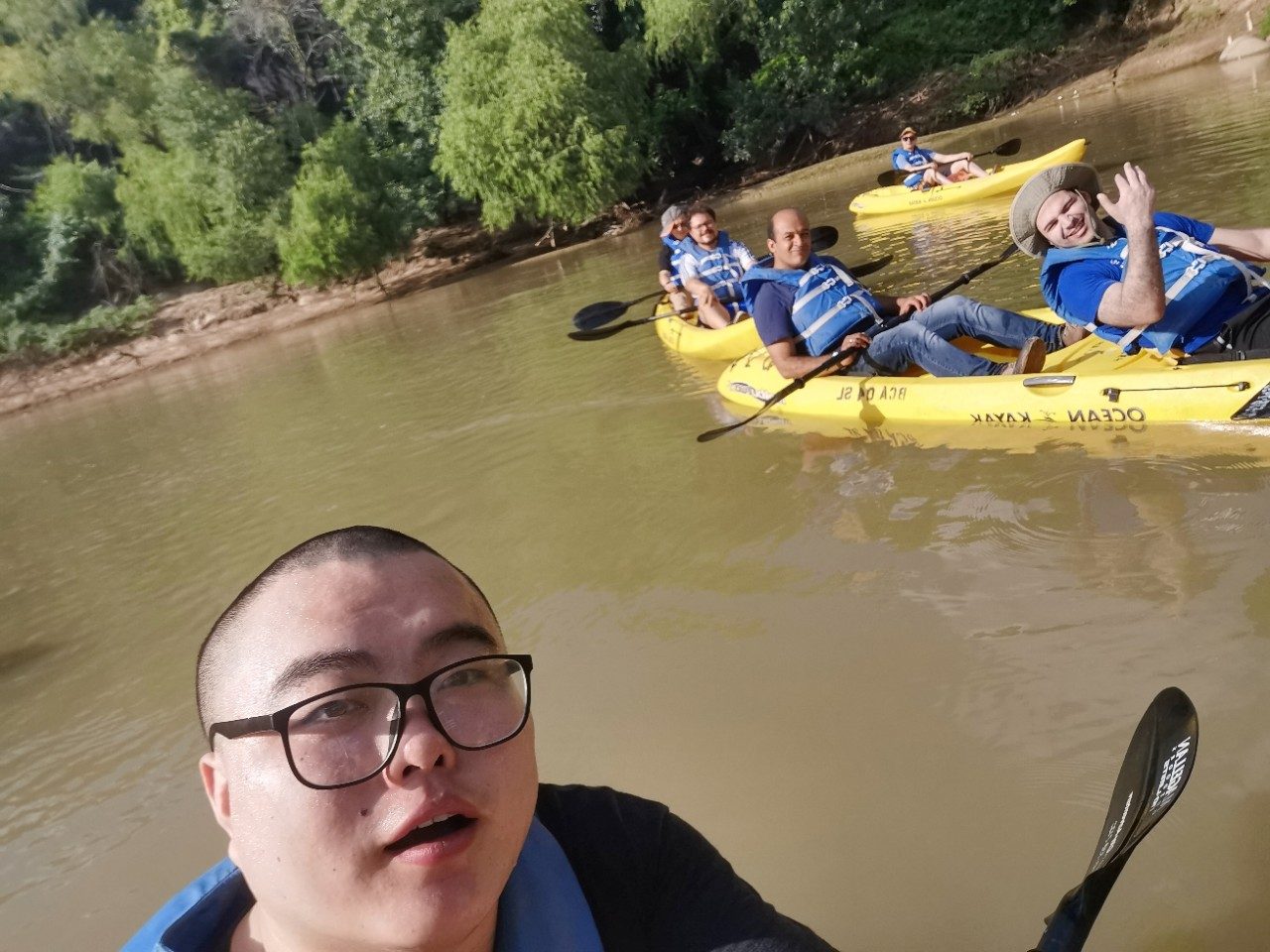 Selfie of one person in the foreground and two kayaks with other folks in the background
