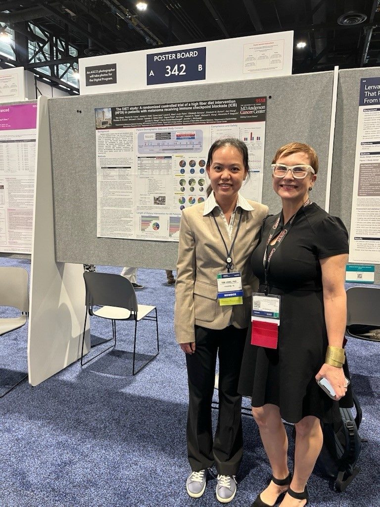 Two women stand in front of a scientific poster
