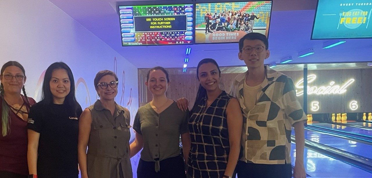 Six people stand in a bowling alley