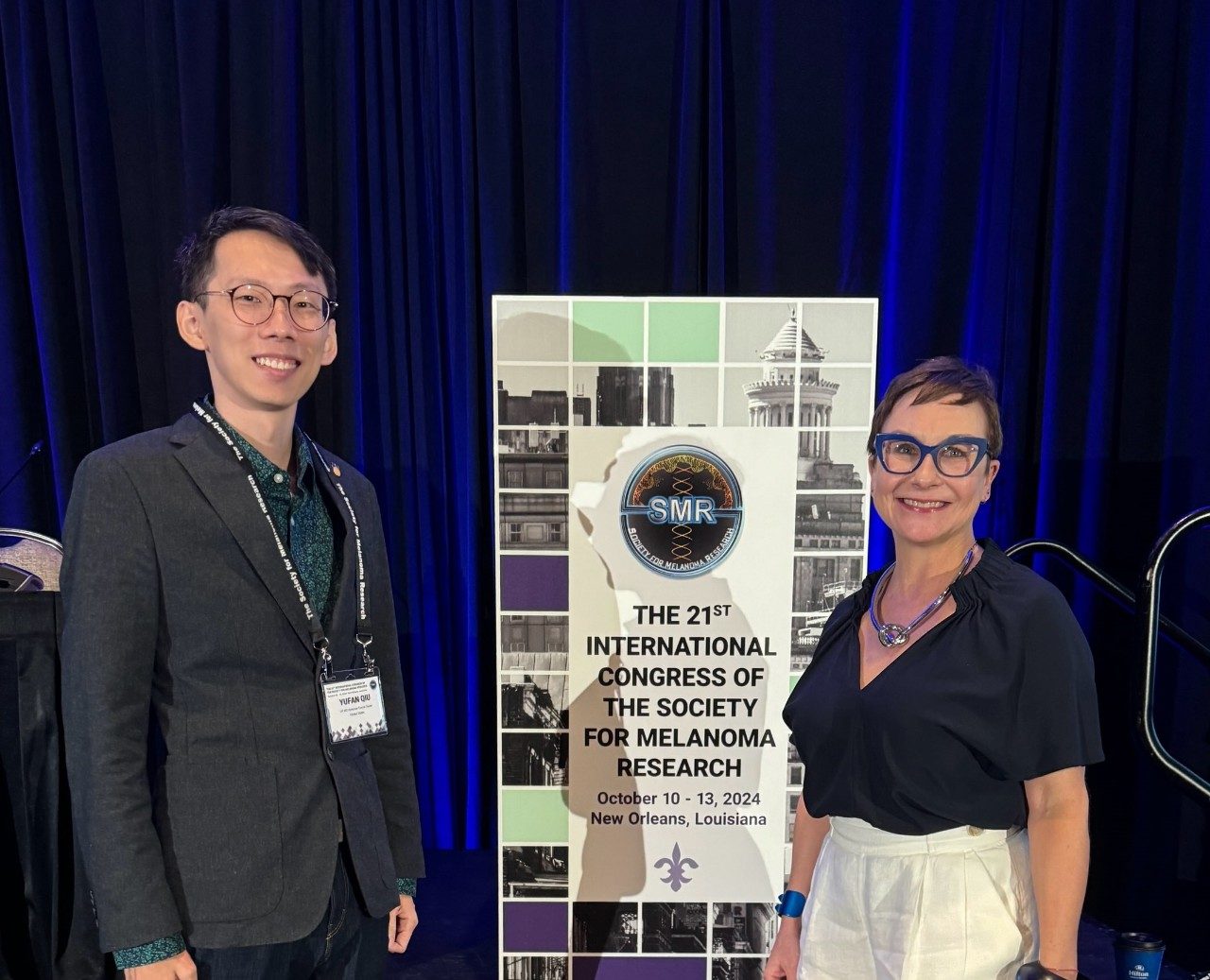 Two people stand near a banner