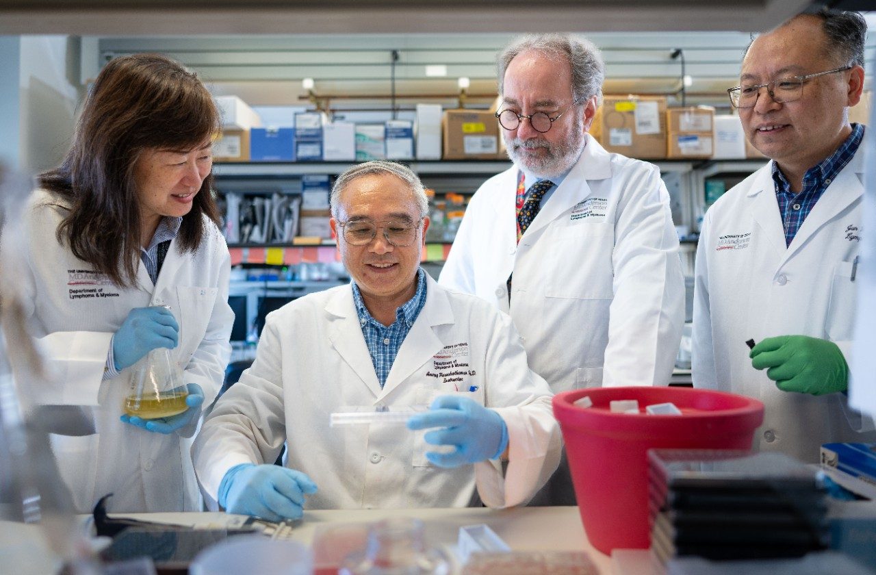 Four people working at a lab benc