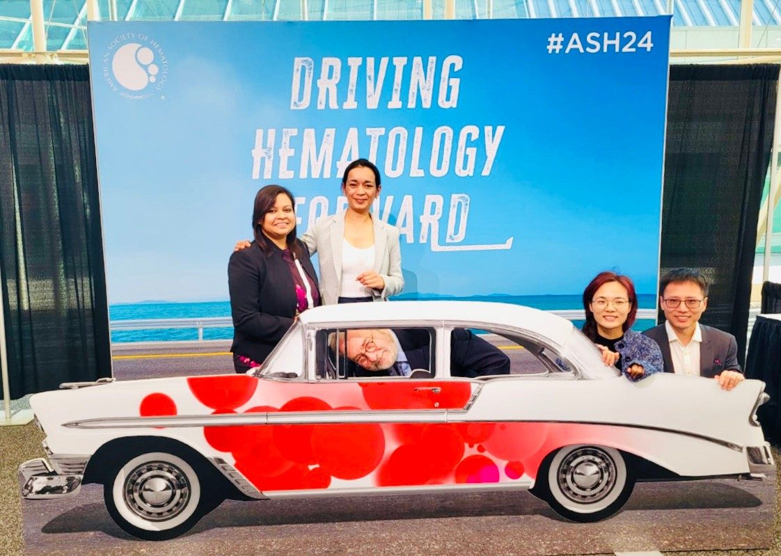 Four people posed around a fake car with Dr. Orlowski peering out of the car window