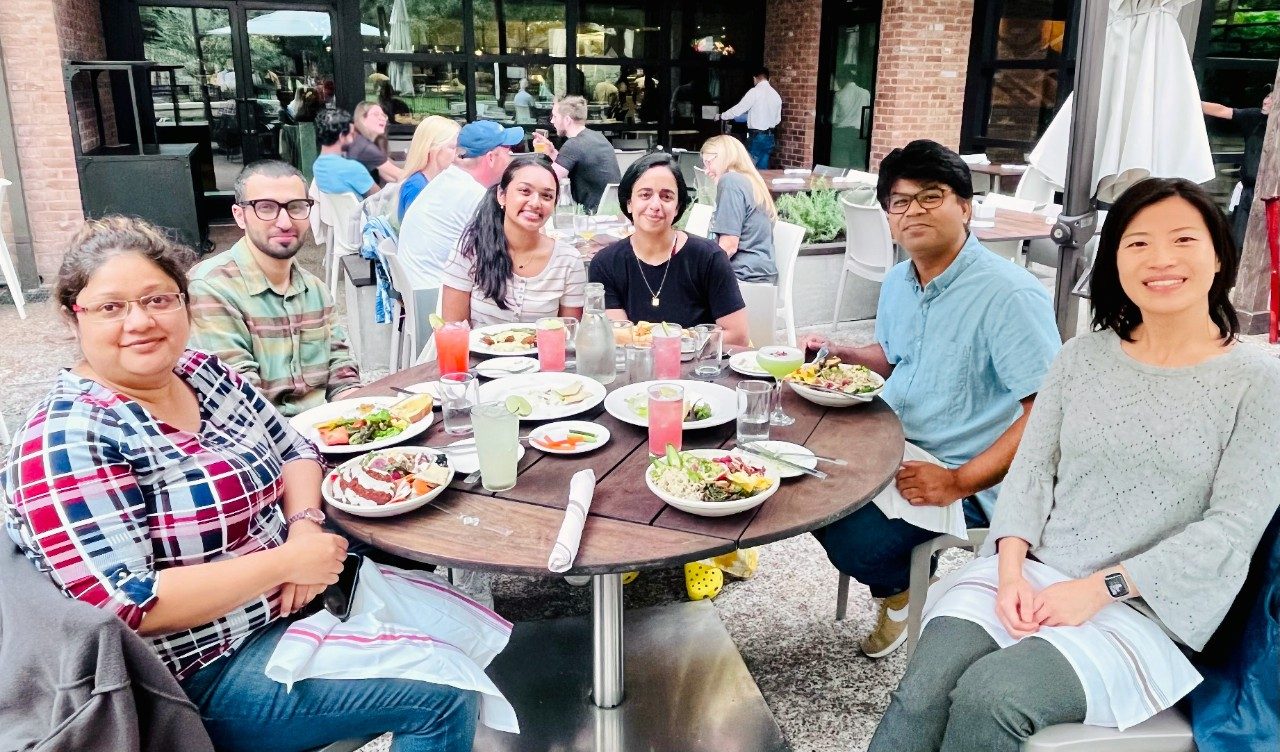 Photo of Pan Lab members sitting at a table of food outdoors 