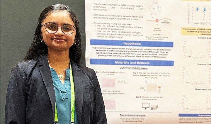 Photo of Pan Lab member Aishani Gargapati by a poster