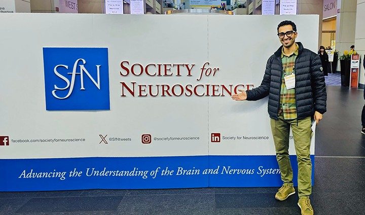 Photo of Pan Lab member Khalil Kasm standing by a Society for Neuroscience poster