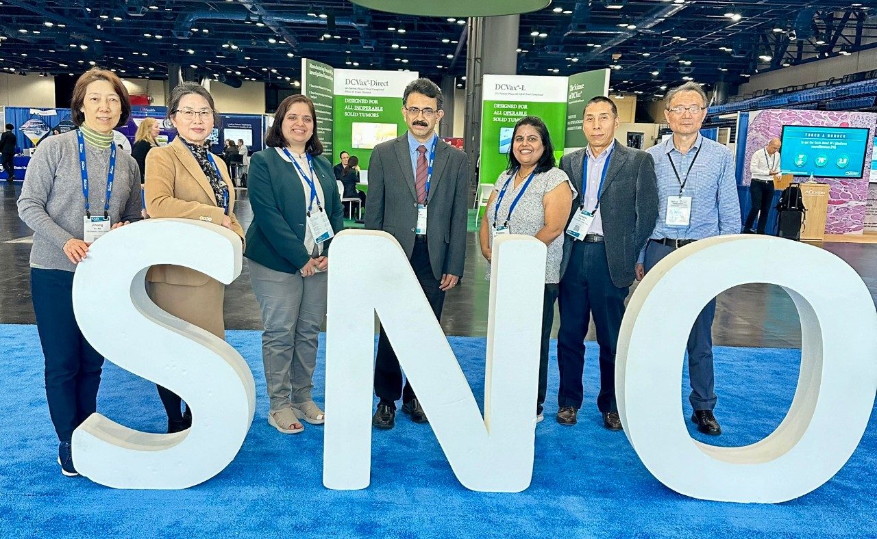 Seven people posed behind giant letters that spell out SNO