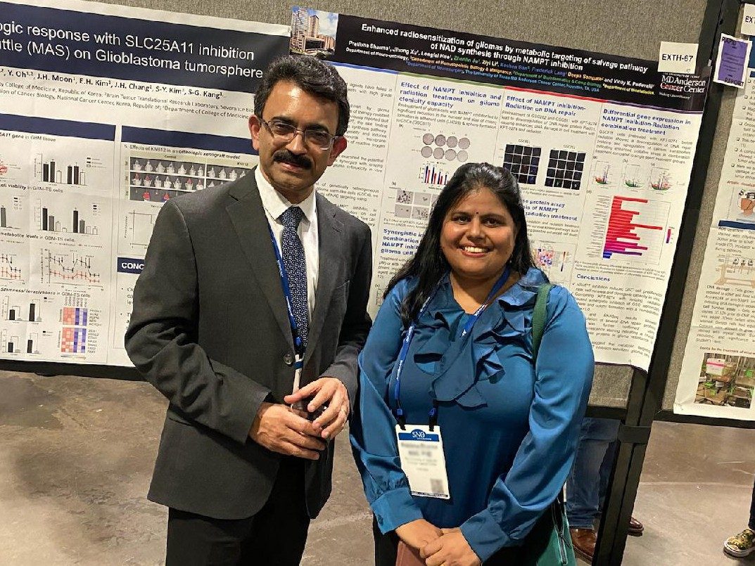 Two people posed in front of a poster