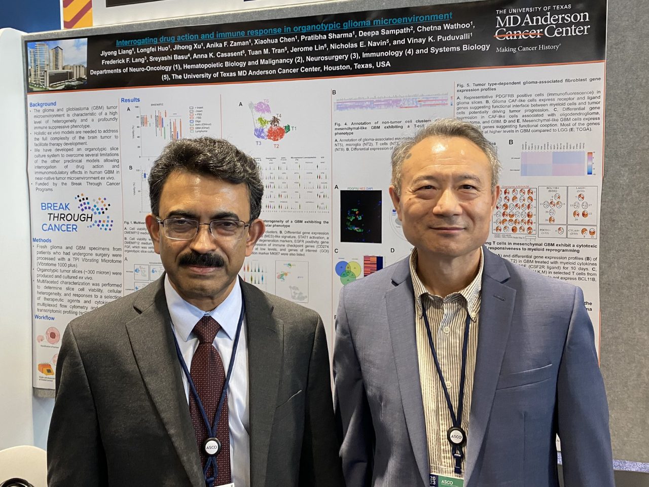 Two people posed in front of a poster