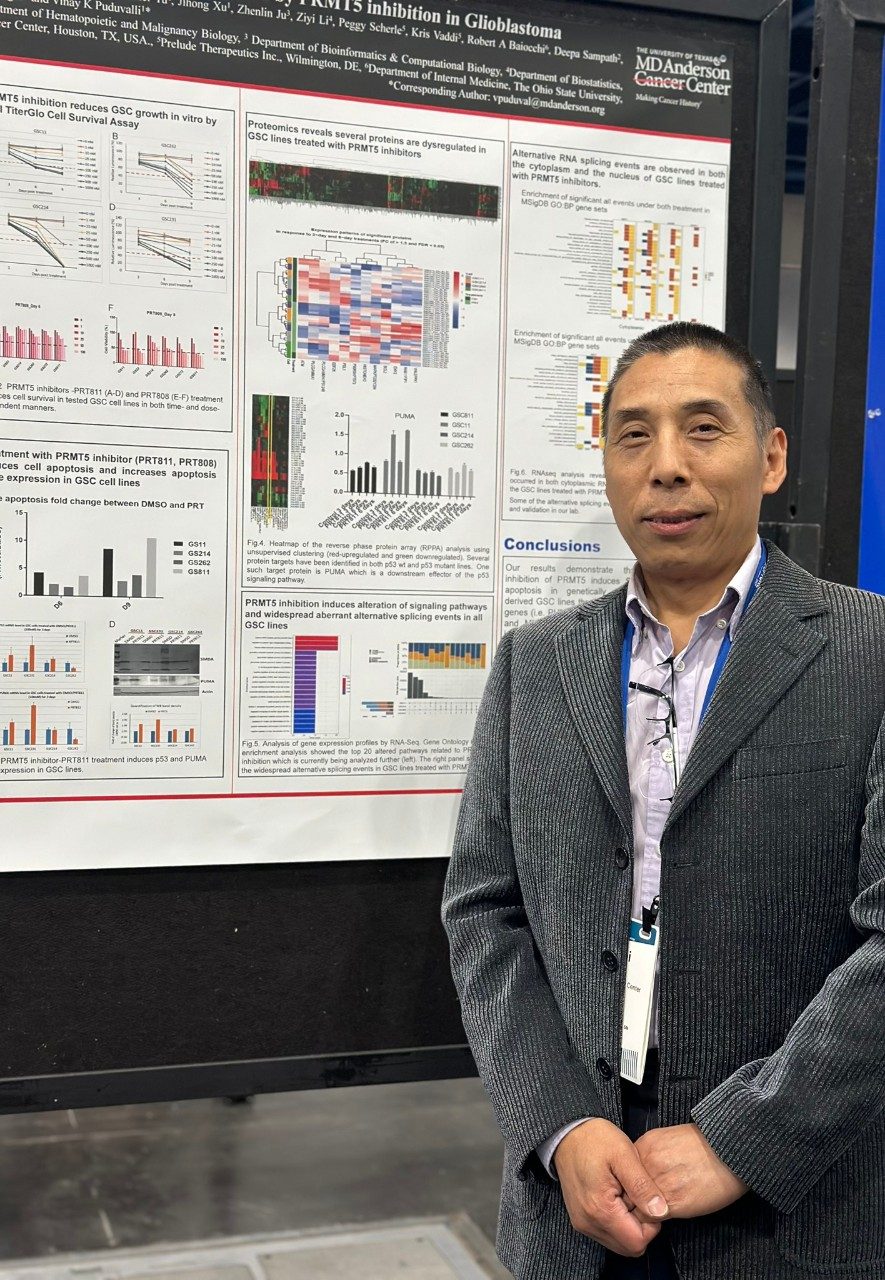 Man in a suit posing next to a poster