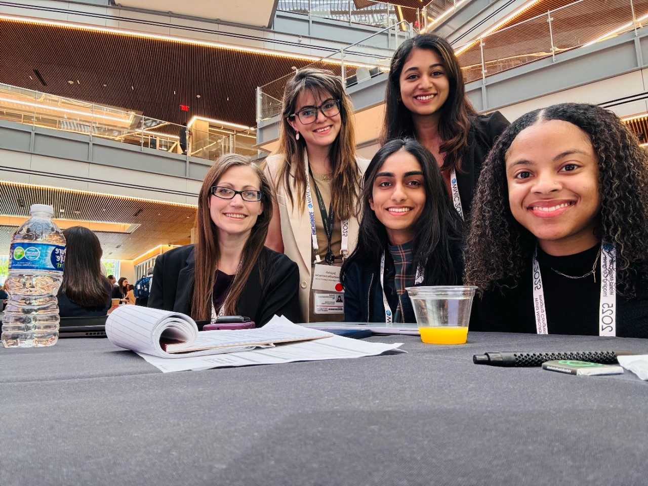 Five people taking a selfie at a table from a phone placed on the table in front of them