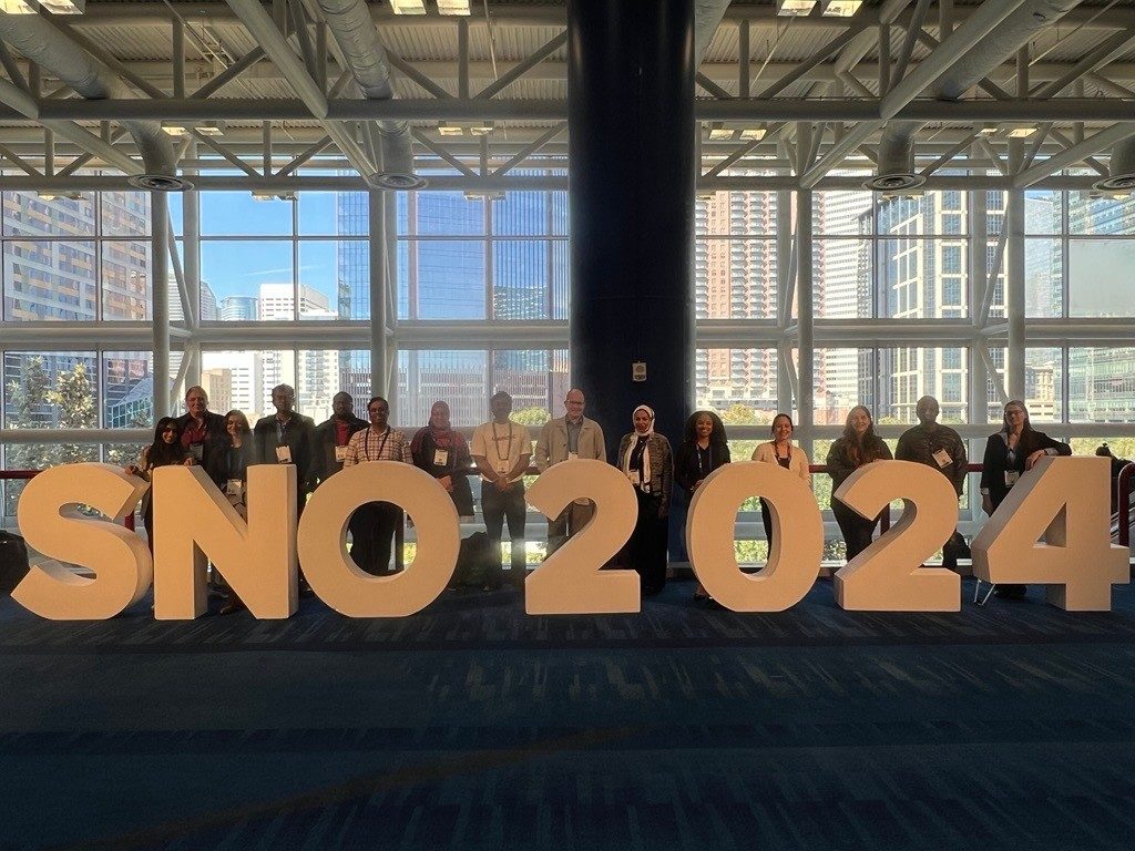 Lab members lined up behind a large SNO 2024 sign