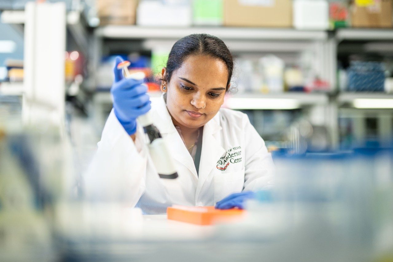 Lab member pipetting at a bench in lab