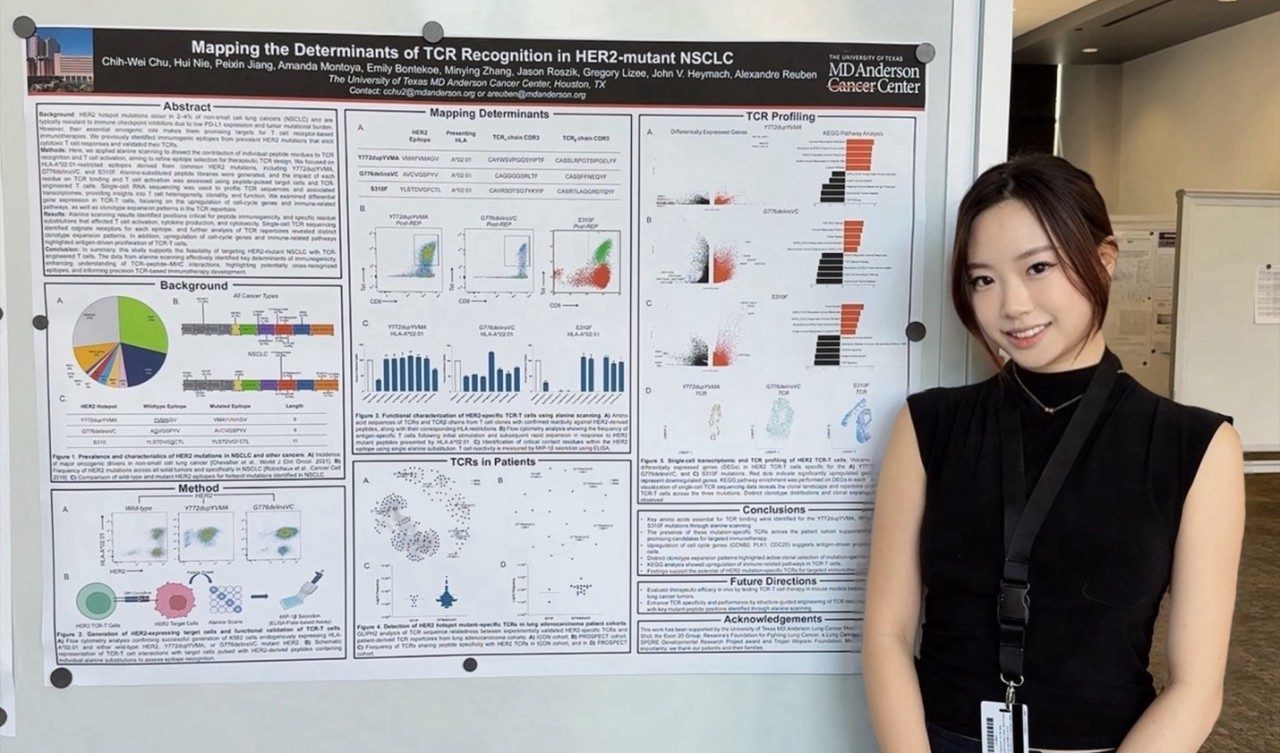 A woman stands in front of a poster