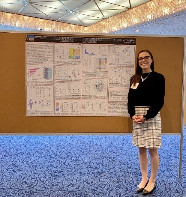 A woman stands in front of a poster