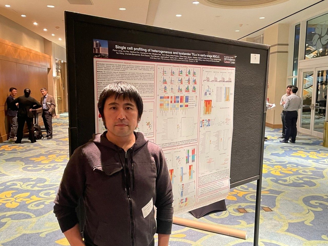 Peixin posing next to his poster