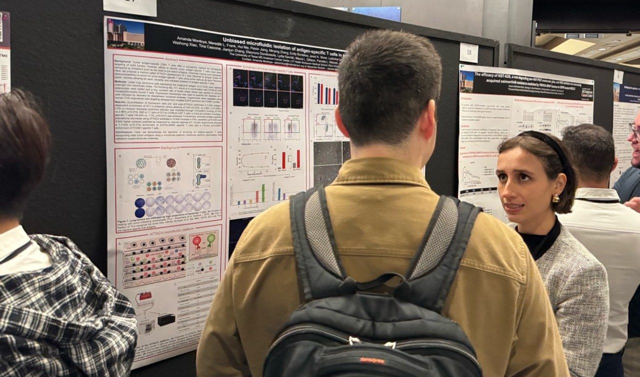 A woman talks to a man in front of a poster
