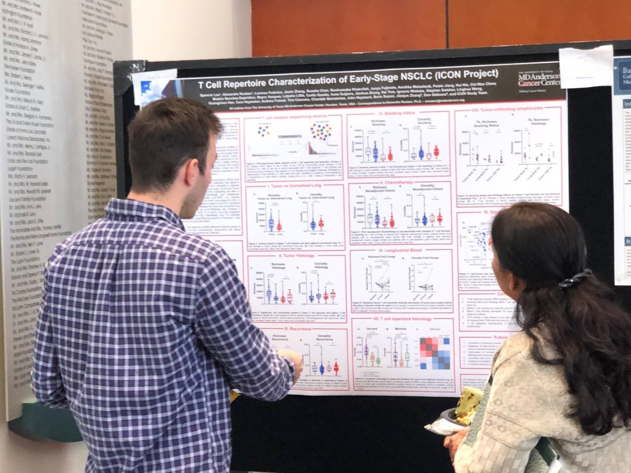 A man points to something on a poster while a woman looks on