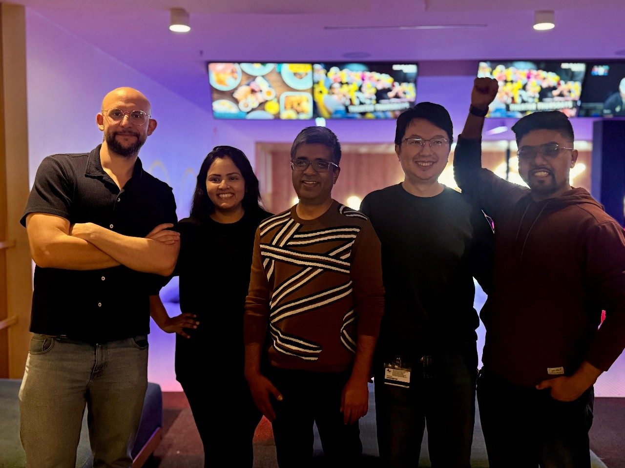 Five members of the Thandapani lab in a line, smiling, with dim lighting