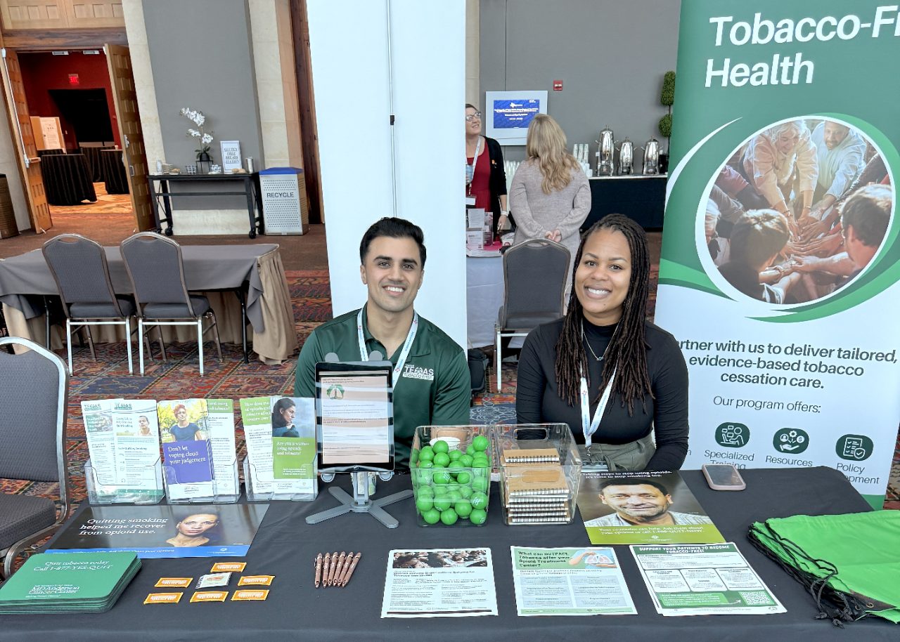 Two people seated behind a table covered with smoking cessation information