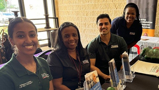 Four people behind a table with materials