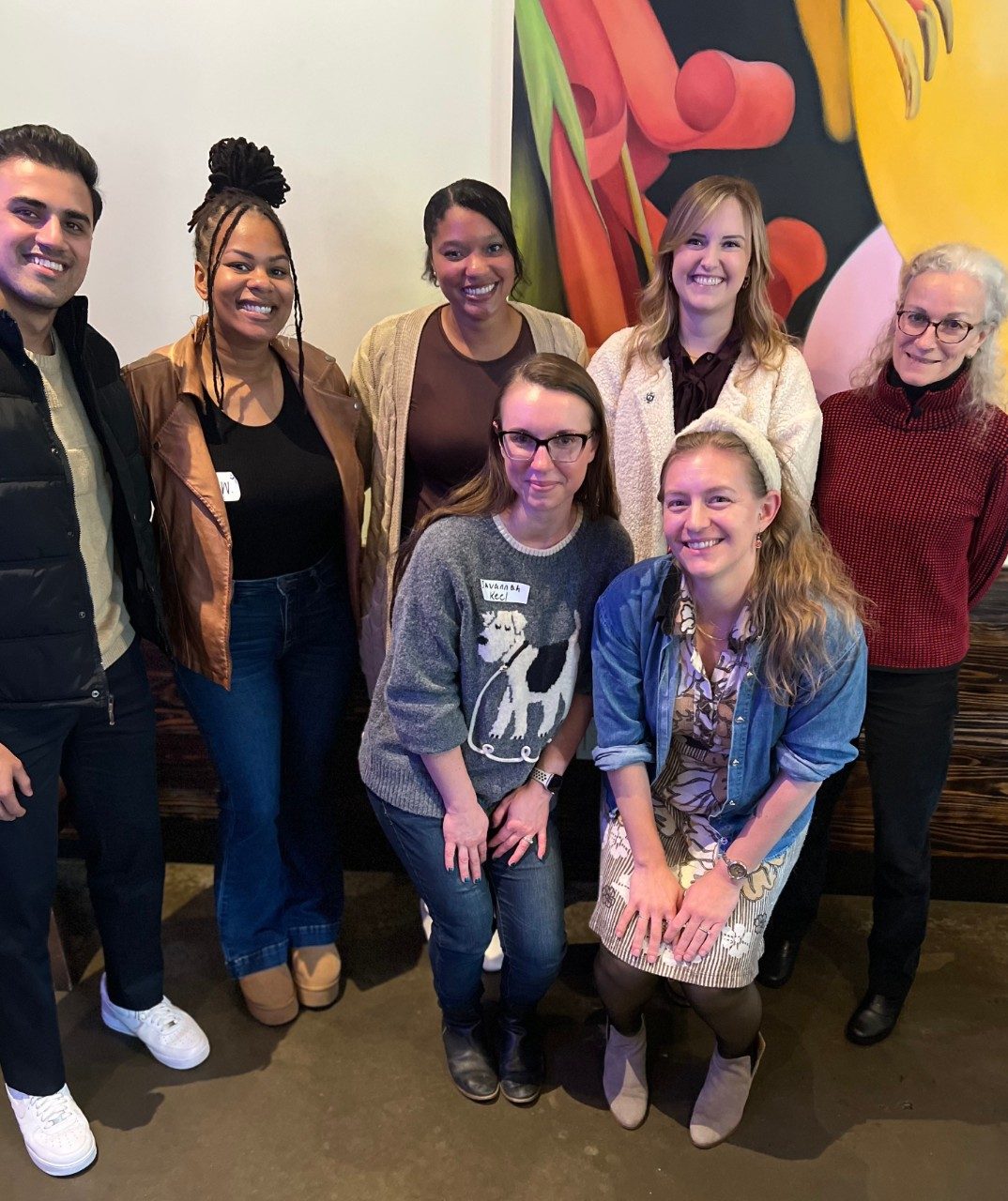 Group photo of 7 people in front of a piece of artwork