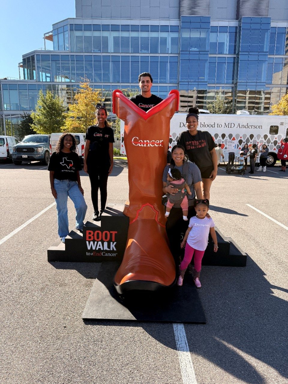 Five adults and two kids pose around the giant branded boot at the MD Anderson 2025 Boot Walk